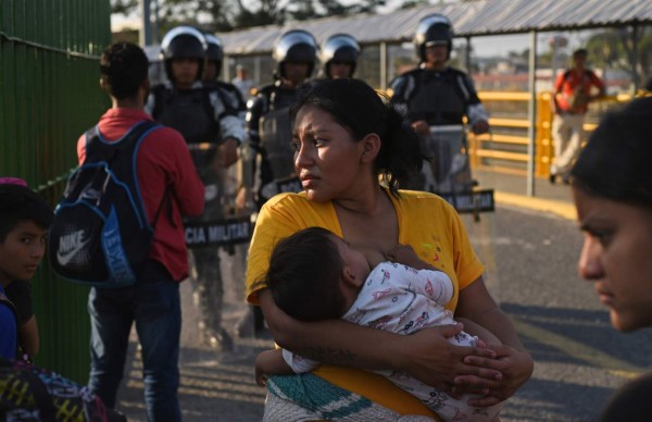 Honduran migrant wait to cross the international border bridge from Ciudad Tecun Uman in Guatemala to Ciudad Hidalgo in Mexico, on January 18, 2020. - On the eve, Mexican President Andres Manuel Lopez Obrador offered 4,000 jobs to members of the caravan in an attempt to dissuade them from traveling on to the United States. The caravan, which formed in Honduras this week, currently has around 3,000 migrants, Lopez Obrador said. (Photo by Johan ORDONEZ / AFP)