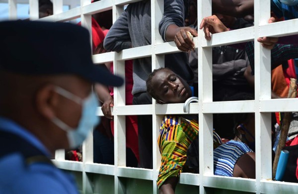 A policeman looks at migrants heading in a caravan to the border with Guatemala who remain onboard a truck after being stopped in Cerro Hula, 10 km south of Tegucigalpa, on June 3, 2020. - Almost a hundred migrants from Congo, Ghana, Ivory Coast, Haiti and Cuba heading in a caravan from Choluteca, Honduras to Mexico were stopped by the police for sanitary controls amid the new coronavirus pandemic. (Photo by ORLANDO SIERRA / AFP)