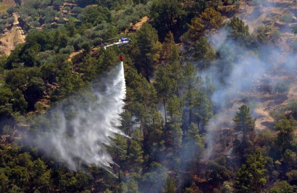 A fire fighting helicopter drops water over a fire near the village of Alijo, on July 18, 2017 during a wildfire.A month after the deadliest forest fire in Portugal's recent history, nearly 2,800 firefighters were working since last night to protect homes in the north and center of the country. / AFP PHOTO / MIGUEL RIOPA