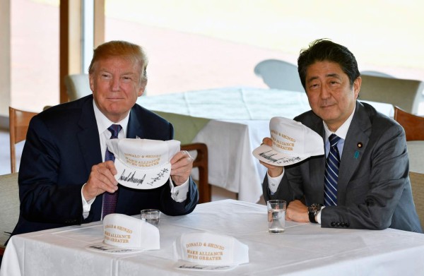 US President Donald Trump (L) and Japanese Prime Minister Shinzo Abe pose after they signed hats reading 'Donald and Shinzo, Make Alliance Even Greater' at the Kasumigaseki Country Club in Kawagoe, near Tokyo on November 5, 2017. Trump touched down in Japan, kicking off the first leg of a high-stakes Asia tour set to be dominated by soaring tensions with nuclear-armed North Korea. / AFP PHOTO / POOL / FRANCK ROBICHON