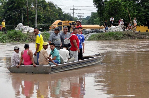 incomunicados. Un grupo de vecinos del sector de Amapa cruzan un canal de alivio del río Ulúa a bordo de una canoa.