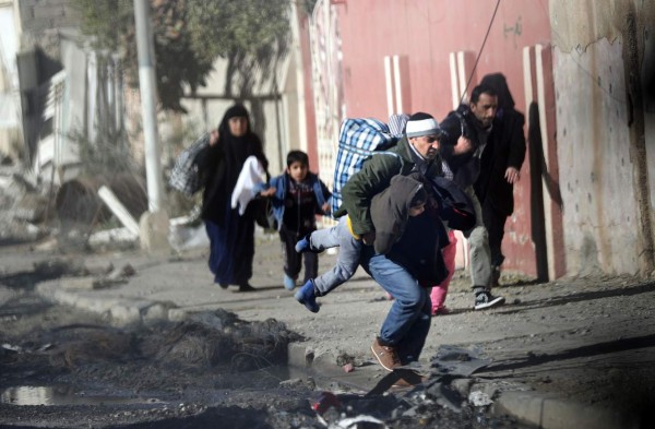 A picture taken through the bulletproof windshield of an Iraqi Special Forces armoured vehicle on November 24, 2016, shows Iraqis running for cover, as Islamic State (IS) group fighters clash with government forces, in a northeastern district of the city of Mosul.Elite forces gained new ground in east Mosul, looking for fresh momentum as stiffer-than-expected IS resistance threatened to bog down the five-week-old offensive against the jihadists' last major stronghold in Iraq. / AFP PHOTO / THOMAS COEX