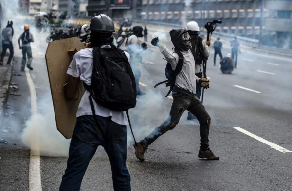 Demonstrators clash with the riot police during a march against President Nicolas Maduro in Caracas, on May 13, 2017. Daily clashes between demonstrators -who blame elected President Nicolas Maduro for an economic crisis that has caused food shortages- and security forces have left 38 people dead since April 1. Protesters demand early elections, accusing Maduro of repressing protesters and trying to install a dictatorship. / AFP PHOTO / Juan BARRETO