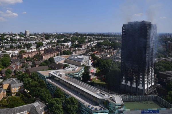 Grenfell Tower smoulders after a fire ripped through the building in west London on June 14, 2017.At least six people were killed Wednesday when a massive fire tore through a London apartment block overnight, with survivors voicing anger over longstanding safety fears at the 24-storey Grenfell Tower. / AFP PHOTO / Ben STANSALL