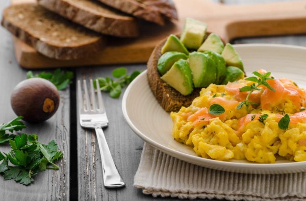 Scrambled eggs with smoked salmon and whole wheat toast with avocado and lemon