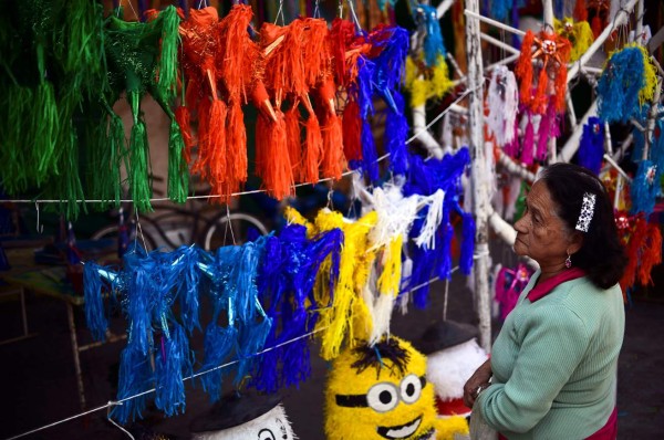 A woman looks at traditional Mexican 'pinatas' for sale at a market in Acolman, Mexico state, on December 18, 2017. The pinata -a papier mache party decoration filled with candy that is hung up at parties and struck with a stick until it breaks open- is a central element of the Mexican Christmas holidays, forming part of a deep-rooted tradition that mixes indigenous customs and the evangelising zeal of the Augustinians in the sixteenth century. / AFP PHOTO / RONALDO SCHEMIDT / TO GO WITH AFP STORY by YEMELI ORTEGA
