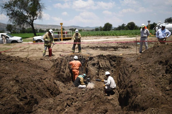 Workers of state-owned oil giant PEMEX repair a leak in a clandestine fuel siphoning area in Tepeaca, Puebla State, Mexico on May 26, 2017. Violent clashes between troops and suspected oil thieves have left a dozen dead, including several soldiers. / AFP PHOTO / ALFREDO ESTRELLA