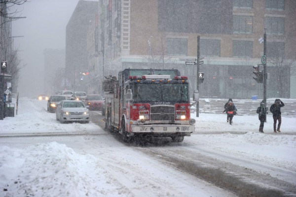 An emergency vehicle drives in snow in downtown Montreal where a snowtorm swept eastern Canada, on December 29, 2015. Snow blanketed eastern Canada, causing airport delays and trouble on the roads as the season's first major winter storm hit the region. AFP PHOTO / Marc BRAIBANT