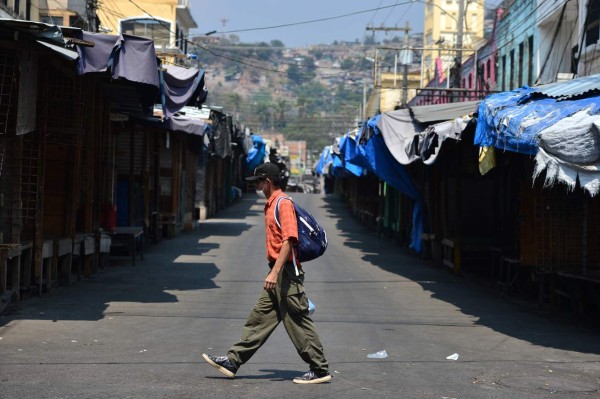 A man wearing a face mask walks across an empty street amid the 'absolute curfew' ordered by the Honduran government to slow the spread of the new coronavirus, COVID-19 in Tegucigalpa on April 4, 2020. - The number of people infected with COVID-19 reached 264 and 15 deaths, in the Central American country. (Photo by ORLANDO SIERRA / AFP)