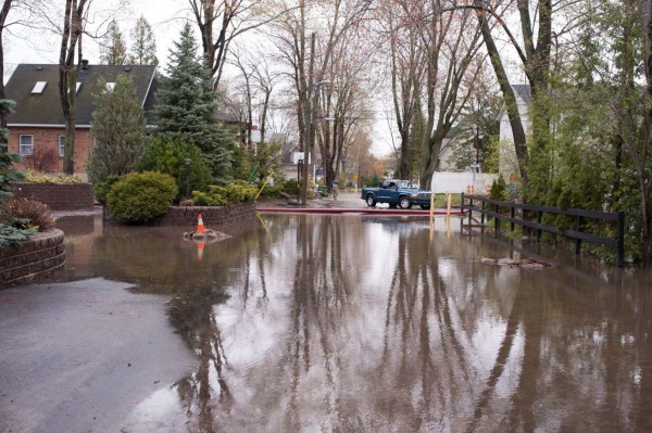 TOPSHOT - A car is park at an intersection in the city of Pierrefonds after heavy flooding caused by unrelenting rain in Central and Eastern Canada on May 7,2017.More than 130 communities in the province have been hit by the flooding, with an estimated 1,500 homes affected and 850 people forced to evacuate. / AFP PHOTO / Catherine Legault