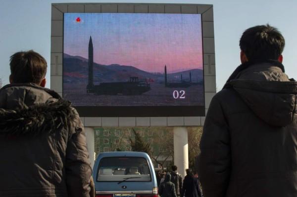 TOPSHOT - People watch news footage of a missile launch on a giant television screen outside the main railway station in Pyongyang on March 7, 2017.Nuclear-armed North Korea said its missile launches were training for a strike on US bases in Japan, as global condemnation of the regime swelled. / AFP PHOTO / KIM Won-Jin