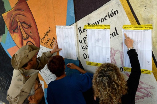 People look for their names on electoral rolls before voting in the municipal elections in Caracas on December 10, 2017. / AFP PHOTO / FEDERICO PARRA