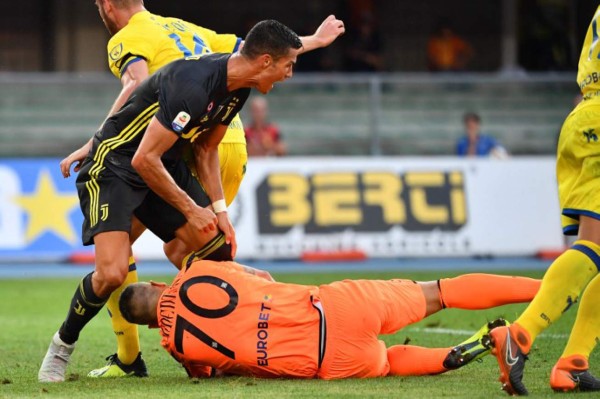 Juventus' Portuguese forward, Cristiano Ronaldo (L) collides with Chievo's goalkeeper Stefano Sorrentino (Bottom) during the Italian Serie A football match AC Chievo vs Juventus at the Marcantonio-Bentegodi stadium in Verona on August 18, 2018. / AFP PHOTO / Alberto PIZZOLI