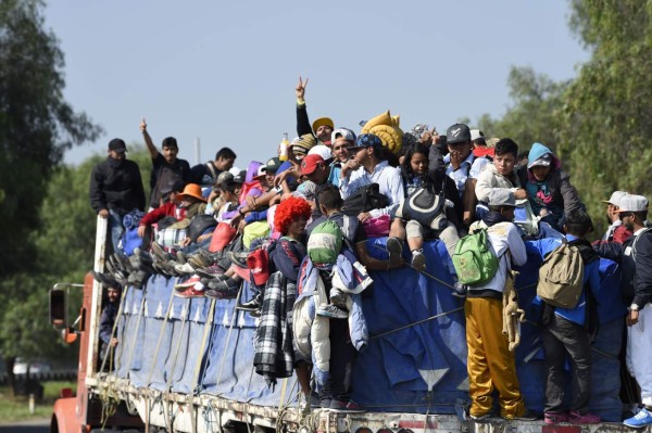 Central American migrants -mostly honduran- taking part in a caravan to the US, on board a truck heading to Irapuato in the state of Guanajuato on November 11, 2018 after spending the night in Queretaro in central Mexico. - The United States embarked Friday on a policy of automatically rejecting asylum claims of people who cross the Mexican border illegally in a bid to deter Central American migrants and force Mexico to handle them. (Photo by Alfredo ESTRELLA / AFP)