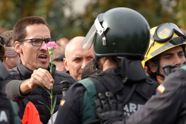 A man holds a carnation in front of Spanish Guardia Civil officers outside a polling station in San Julia de Ramis, on October 1, 2017, on the day of a referendum on independence for Catalonia banned by Madrid.More than 5.3 million Catalans are called today to vote in a referendum on independence, surrounded by uncertainty over the intention of Spanish institutions to prevent this plebiscite banned by justice. / AFP PHOTO / LLUIS GENE