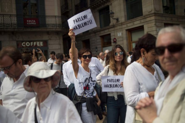 Protesters hold placards reading 'Let's talk' during a demonstration called by the 'Let's talk' (Parlem,Hablemos) association for dialogue in Catalonia in October 07, 2017 in Barcelona.Spain braced for more protests despite tentative signs that the sides may be seeking to defuse the crisis after Madrid offered a first apology to Catalans injured by police during their outlawed independence vote. / AFP PHOTO / LLUIS GENE