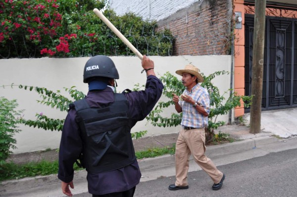 A riot police officer brandishes his truncheon against a protestor during a demonstration in front of Radio Globo's building in Tegucigalpa on September 30, 2009. Scores of soldiers and police surrounded the INRA, which several hundred farm workers had been using as temporary housing in order to attend protests in the capital against the June 28 coup, and detained 55 of them, including six women. A top official from the Organization of American States on Wednesday said dialogue between deposed President Manuel Zelaya and the leaders of the June 28 coup could start next week. AFP PHOTO/Yuri CORTEZ