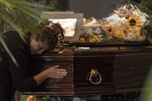 A mourner prays at the coffin of a victim of the Morandi bridge collapse at a funerary home installed at the fairground in Genoa, on August 17, 2018.Grieving relatives wept over coffins of dozens of victims of Genoa's bridge collapse on August 17, 2018, as controversy clouded a planned state funeral, while rescuers pressed on with their formidable search for those missing in the rubble. Fury is growing over the shock collapse of the Morandi bridge, a decades-old viaduct that crumbled in a storm on August 14 killing at least 38 people, with Italian media reporting that some outraged families would shun August 19's official commemorations. / AFP PHOTO / MARCO BERTORELLO