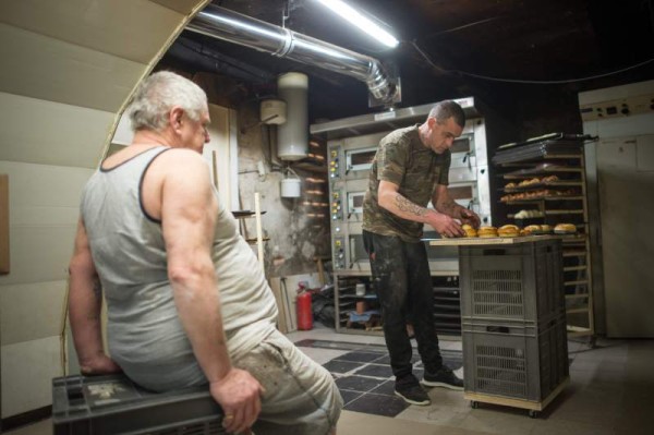 El panadero de 62 años, tomando asiento sobre unos cajones de plástico para descansar sus piernas fatigadas por la artrosis.