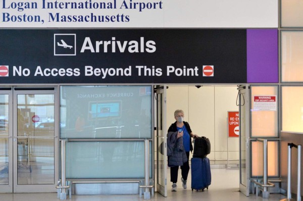 People arrive, some in masks, off a flight from Amsterdam into the arrivals area at terminal E at Logan Airport in East Boston, Massachusetts on March 13, 2020. - US President Donald Trump declared the novel coronavirus, COVID-19, a national emergency on March 13, 2020. (Photo by Joseph Prezioso / AFP)