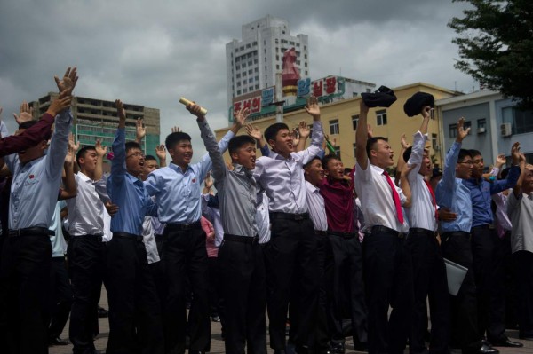 People gesture as coverage of an ICBM missile test is displayed on a screen in a public square in Pyongyang on July 29, 2017.Kim Jong-Un boasted of North Korea's ability to strike any target in the US after a second ICBM test that weapons experts said on July 29 could even bring New York into range - in a potent challenge to President Donald Trump. / AFP PHOTO / Kim Won-Jin
