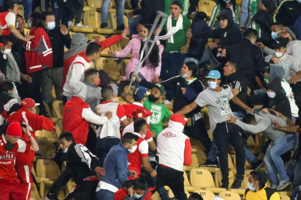 Supporters of the Independiente Santa Fe and Atletico Nacional teams clash inside the Nemesio Camacho El Campin stadium during its reopening to the public after being closed by the Covid-19 pandemic in Bogota on August 3, 2021. (Photo by Daniel Garzon / AFP)