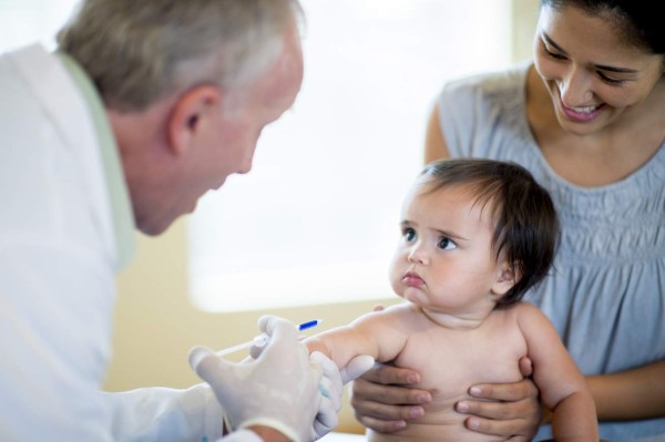 A baby girl with her mother at an appointment with a doctor getting her immunization, vaccines, and shots.