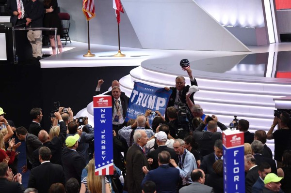 Supporters of Donald Trump march across the convention floor July 18, 2016 on the first day of the Republicna National Convention in Cleveland, Ohio.The Republican Party opened its national convention Monday, kicking off a four-day political jamboree that will anoint billionaire Donald Trump as its presidential nominee. Some 2,000 delegates descended on a tightly secured Cleveland arena where Trump's wife will take center stage later in the day to make a personal pitch to voters that her billionaire husband is the best candidate for the White House. / AFP PHOTO / Robyn BECK