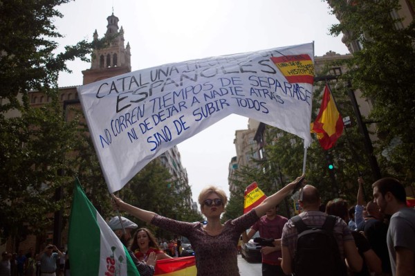 A woman holds a placard reading 'Catalonia made by Spaniards. It is not time for separation. Do not leave anyone behind' as she confronts demonstrators in support of the referendum in Catalonia on October 01, 2017, in Granada. / AFP PHOTO / JORGE GUERRERO