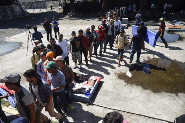 Central American migrants - mostly Hondurans- taking part in a caravan heading to the US, line up to borrow a sleeping pad, after arriving at a temporary shelter, set up in a stadium in Mexico City, during a stop in their journey, on November 05, 2018. - Some 2,000 migrants en route to US recover energy Monday in a shelter in Mexico City, where they await the arrival of thousands more. US President Donald Trump warned that up to 15,000 soldiers could be deployed in the border with Mexico to stop the migrants' attempt to cross illegally into the country. (Photo by ALFREDO ESTRELLA / AFP)