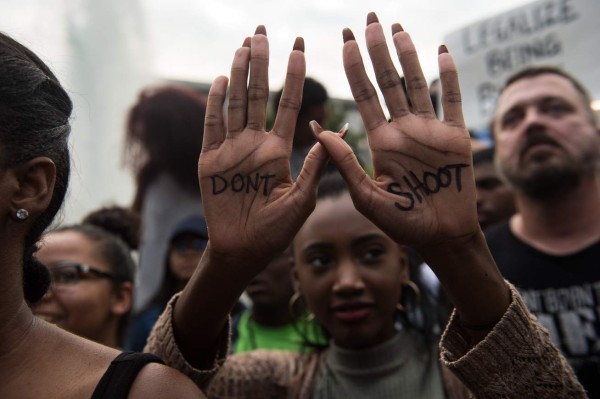 A protester holds up her hands with a slogan written on them during a demonstration against police brutality in Charlotte, North Carolina, on September 21, 2016, following the shooting of Keith Lamont Scott the previous day.A protester shot during a second night of unrest in Charlotte, North Carolina was critically wounded, the city said, after earlier reporting that the person had died. / AFP PHOTO / NICHOLAS KAMM