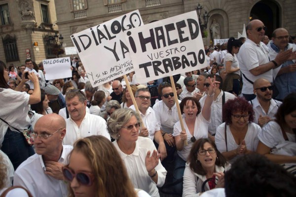 Protesters hold placards reading 'Dialogue now' and 'Do your job' during a demonstration called by the 'Let's talk' (Parlem,Hablemos) association for dialogue in Catalonia in October 07, 2017 in Barcelona.Spain braced for more protests despite tentative signs that the sides may be seeking to defuse the crisis after Madrid offered a first apology to Catalans injured by police during their outlawed independence vote. / AFP PHOTO / LLUIS GENE