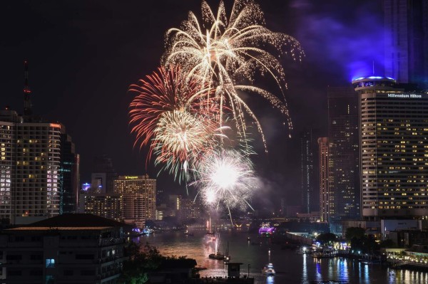 A firework display is seen over the Chao Praya River during New Year celebrations in Bangkok at the start of January 1, 2018. / AFP PHOTO / LILLIAN SUWANRUMPHA