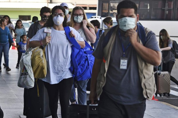 Passengers wear protective face masks to prevent the spread of the new Coronavirus, COVID-19, outside the Toncontin International Airport, in Tegucigalpa, on March 14, 2020. - Honduran government has prohibited citizens from Europe, China, Iran, and South Korea the entrance to the country. (Photo by ORLANDO SIERRA / AFP)