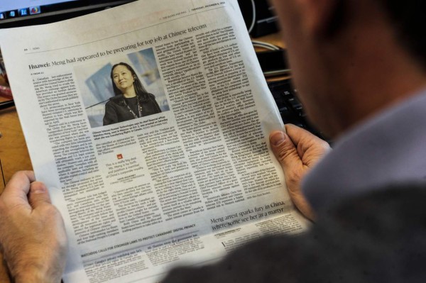 An illustration shows a journalist reading a news page about tech giant Huawei in The Globe and Mail in Montreal, Canada, December 6, 2018. - The arrest of a top executive of Huawei at the request of US authorities signals a toughening stand in Washington on dealing with Chinese tech firms amid longstanding concerns over cyberespionage. Meng Wanzhou (pictured on the news page), Huawei's chief financial officer, was detained this week in Canada and faces an extradition request from US authorities over an investigation into suspected Iran sanctions violations by the Chinese technology giant. (Photo by Clement SABOURIN / AFP) / RESTRICTED TO EDITORIAL USE