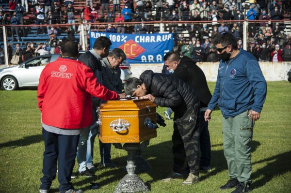 Relatives and friends pay respect at the coffin with the remains of Argentine former football player Tomas 'El Trinche' Carlovich during a homage at the Gabino Sosa stadium in Rosario, Argentina, on May 9, 2020 despite the lockdown imposed by the government against the spread of the new coronavirus, COVID-19. - Tomas Felipe 'Trinche' Carlovich died on the eve after suffering an assault in the central province of Santa Fe. (Photo by STR / AFP)
