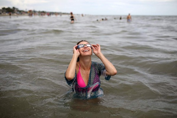 HILTON HEAD ISLAND, SC - AUGUST 21: Molly Moser, from Denver, Colorado, watches the first solar eclipse to sweep across the United States in over 99 years in the Atlantic Ocean August 21, 2017 on Hilton Head Island, South Carolina. Millions of people are expected to watch as the eclipse cuts a path of totality 70 miles wide across the United States from Oregon to South Carolina. Win McNamee/Getty Images/AFP== FOR NEWSPAPERS, INTERNET, TELCOS & TELEVISION USE ONLY ==