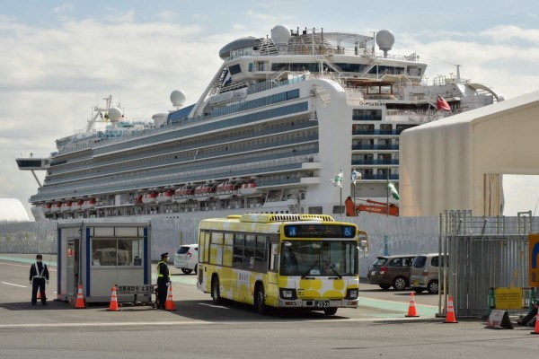 A bus carrying passengers who disembarked from the Diamond Princess cruise ship (back) in quarantine due to fears of the new COVID-19 coronavirus, leaves the Daikoku Pier Cruise Terminal in Yokohama on February 19, 2020. - Relieved passengers began leaving a coronavirus-wracked cruise ship in Japan on February 19 after testing negative for the disease that has now claimed more than 2,000 lives in China. (Photo by Kazuhiro NOGI / AFP)