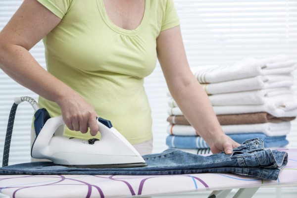 Close up of a woman ironing clothes with a steam iron