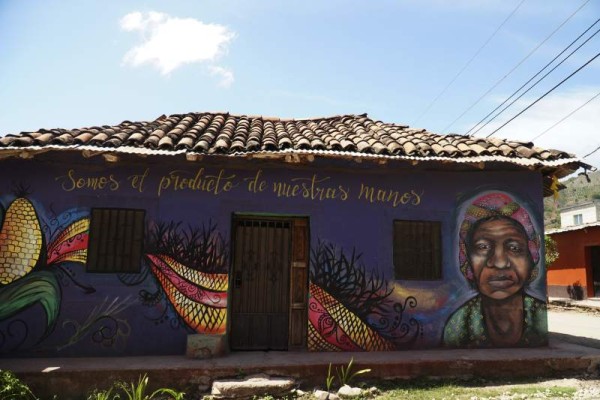Mural de una mujer indígena de la zona alta de Ajuterique que está inspirado en los cultivos. Las casas alrededor del parque se han pintado de blanco caracol y en la parte baja utilizaron la paleta de los colores lencas.