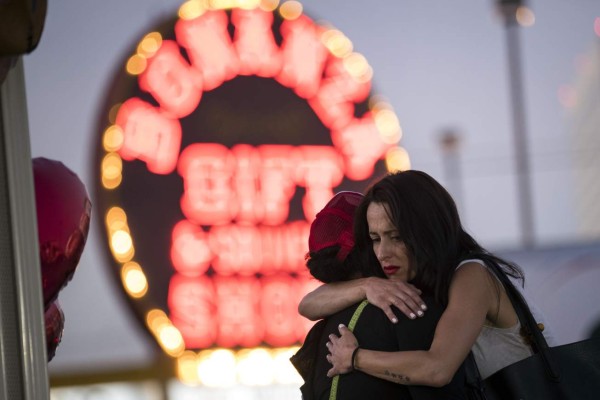 LAS VEGAS, NV - OCTOBER 4: Las Vegas resident Elisabeth Apcar (R) hugs a woman who was working at the concert venue on Sunday night (she wished to remain anonymous), at a makeshift memorial at the northern end of the Last Vegas Strip, October 4, 2017 in Las Vegas, Nevada. On October 1, Stephen Paddock killed at least 58 people and injured more than 450 after he opened fire on a large crowd at the Route 91 Harvest country music festival. The massacre is one of the deadliest mass shooting events in U.S. history. Drew Angerer/Getty Images/AFP== FOR NEWSPAPERS, INTERNET, TELCOS & TELEVISION USE ONLY ==