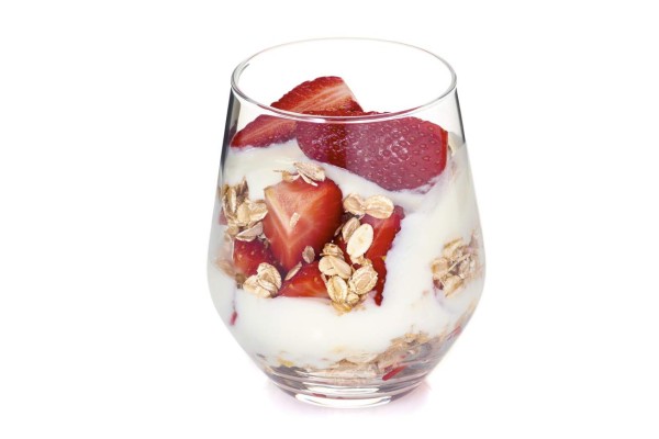 Yogurt with muesli and strawberries in glass isolated on white background