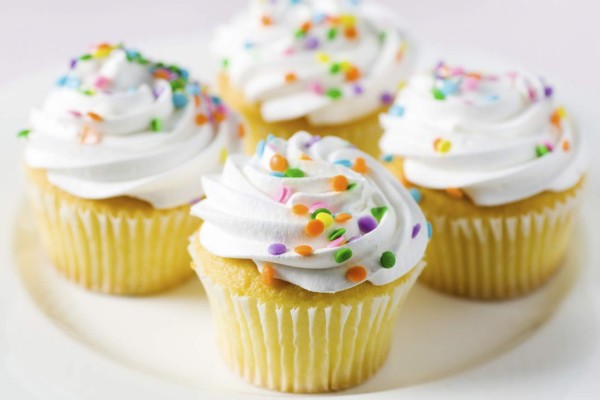Cupcakes with white frosting swirls and colorful confetti. Shallow DOF.