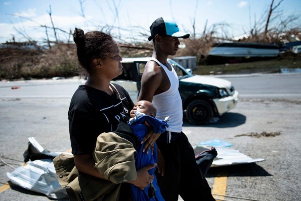 TOPSHOT - Isabel Strachan (L) walks with her son Nathiel Strachan and brother-in-law Kyreem Jonassaind after Hurricane Dorian September 5, 2019, in Marsh Harbor, Great Abaco. - Hurricane Dorian lashed the Carolinas with driving rain and fierce winds as it neared the US east coast Thursday after devastating the Bahamas and killing at least 20 people. (Photo by Brendan Smialowski / AFP)