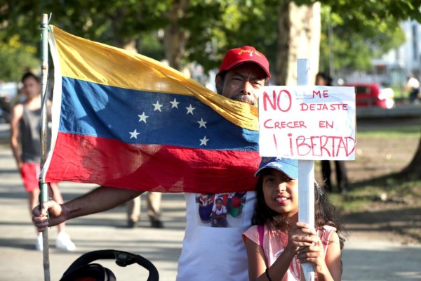 AME1933. PUNTA DEL ESTE (URUGUAY), 23/01/2019.- Un hombre y su hija participan hoy, miércoles en una manifestación de venezolanos que apoyan la autoproclamación del líder de la Asamblea Nacional venezolana, Juan Guiadó, quien anunció que asume las competencias del Ejecutivo de ese país, en Punta del Este (Uruguay). Cientos de venezolanos se concentraron este miércoles para pedir al Gobierno de Uruguay que reconozca a Guiadó. EFE/Raúl Martínez