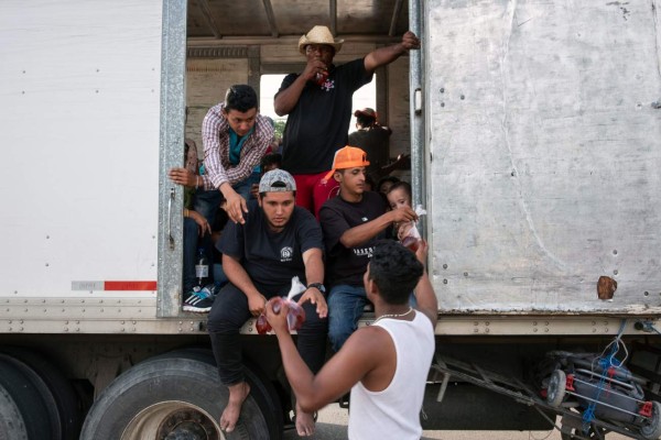 Migrants -mostly Hondurans- taking part in a caravan heading to the US, receive flavoured water from local residents in the Mexican town of Aguilera, as they travel aboard a truck on their way to Acayucan, Veracruz state, Mexico, on November 02, 2018. - President Donald Trump on Thursday warned that soldiers deployed to the Mexican border could shoot Central American migrants who throw stones at them while attempting to cross illegally. (Photo by Guillermo Arias / AFP)