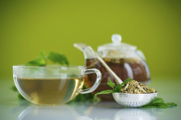 green tea in a glass pot on a green background