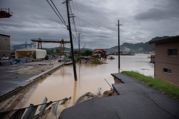 TOPSHOT - This picture shows a broken road following heavy rains and flooding in Mihara on July 8, 2018.Japan's Prime Minister Shinzo Abe warned on July 8 of a 'race against time' to rescue flood victims as authorities issued new alerts over record rains that have killed at least 48 people. / AFP PHOTO / Martin BUREAU