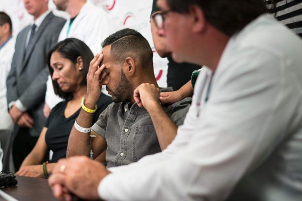 Angel Colon(C), a surviver of the Pulse nightclub mass shooting, listens during a press conference with Orlando Health trauma staff at Orlando Regional Medical Center June 14, 2016 in Orlando, Florida.Two days after 49 people were killed and dozens of others grievously injured in America's deadliest mass shooting, Colon, his voice quivering, recalled how a festive evening out with friends turned into unfathomable horror early Sunday. / AFP PHOTO / Brendan Smialowski