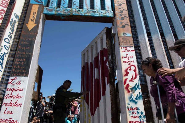 Carmen Guitar walks to meet her family as a US Border Patrol agent opens the gate during the 'Opening the Door of Hope' event at the US-Mexico border fence gate in Playas de Tijuana, Mexico on April 30, 2017.The event, in which members of families living on different sides of the US-Mexico border are briefly reunited, was organized by the Border Angels migrant advocacy group, in coordination with the Tijuana city government and the US Border Patrol. / AFP PHOTO / GUILLERMO ARIAS